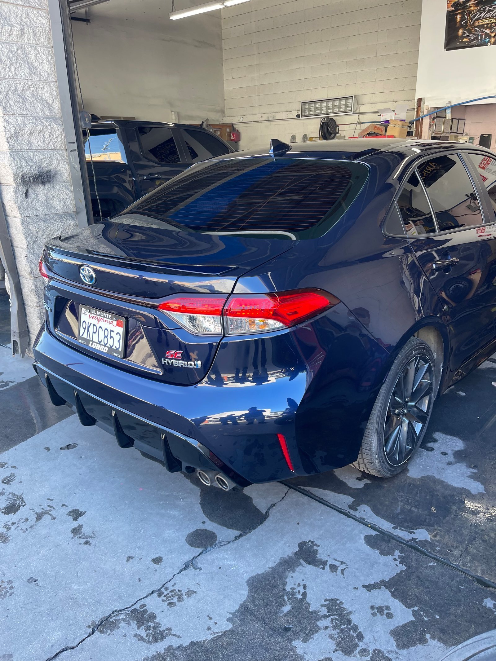 The finished navy Corolla outside the bay, glossy and straight with no sign of the repair